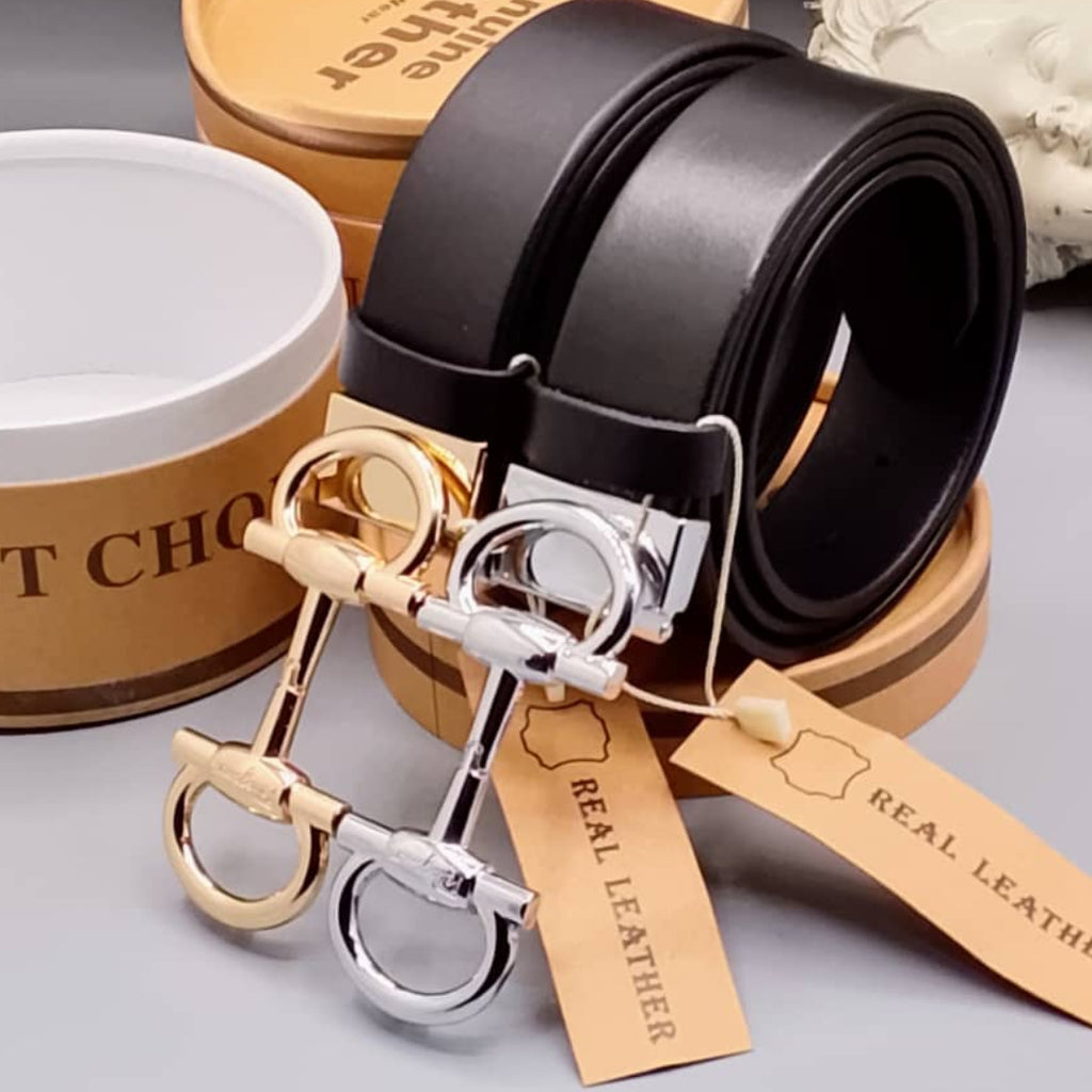 Black leather belt with gold and silver horse bit keychains on a gray surface.